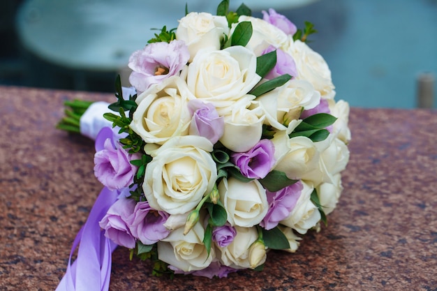 Beautiful wedding bouquet of natural flowers on a blurred background lies on granite