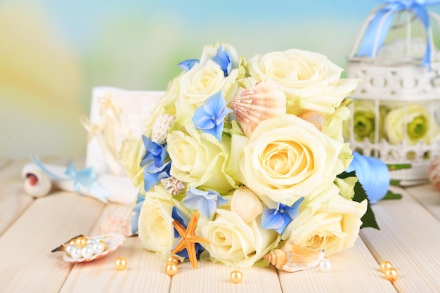 Beautiful wedding bouquet with roses on wooden table, on nature background