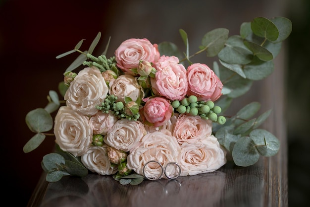 Beautiful wedding bouquet with wedding rings on a wooden table high quality photo