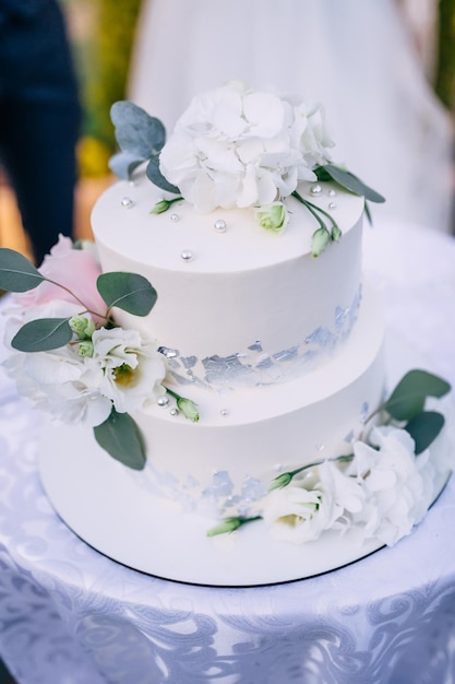 Beautiful wedding cake closeup of a cake decorated with white flowers and green leaves