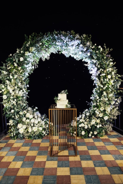 Beautiful wedding cake with flowers and a large wedding arch