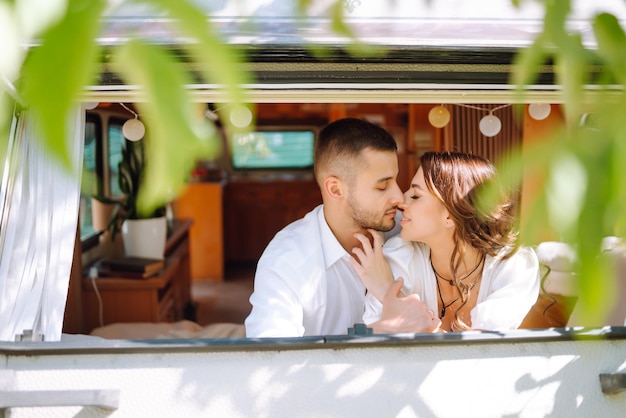 Beautiful wedding couple laugh and kiss relaxing in rv camping in a trailer Romantic moment