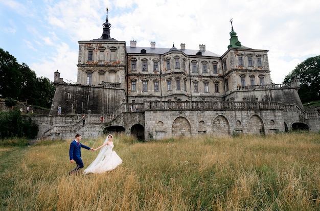 Beautiful wedding couple poses before an old ruined castle