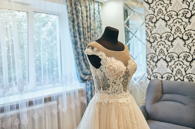 Beautiful wedding dress hanging in the room woman getting ready before ceremony