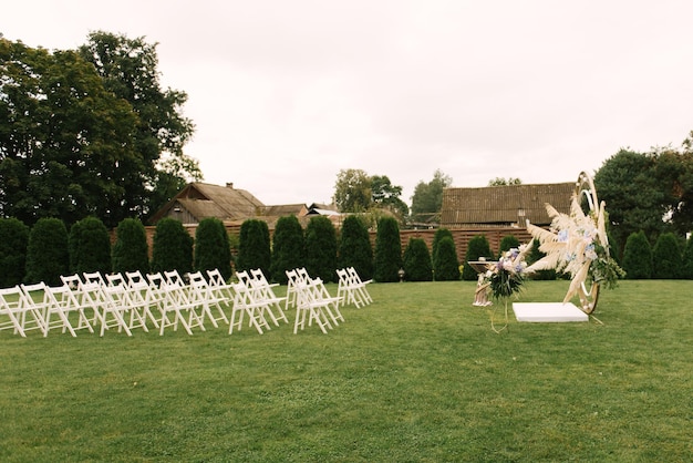 Beautiful wedding for a marriage ceremony in nature decorated with flowers and a lot of white chairs for guests wedding decor