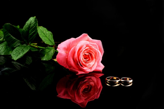 Photo beautiful wedding rings gold for newlyweds with a pink rose