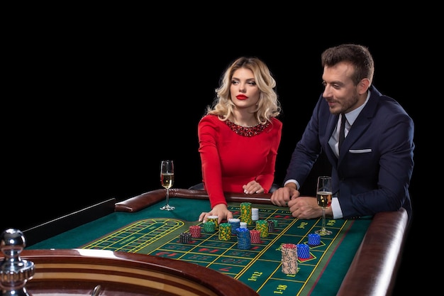 Beautiful and well dressed couple playing roulette in the casino