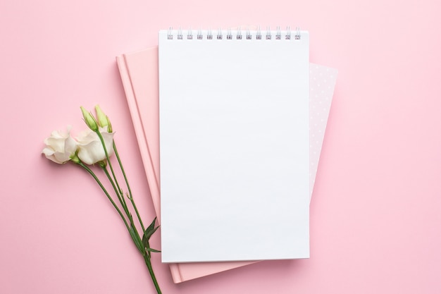 Beautiful white flower and notebook on pink