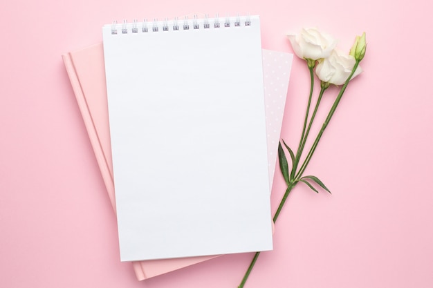 Beautiful white flower and notebook on pink