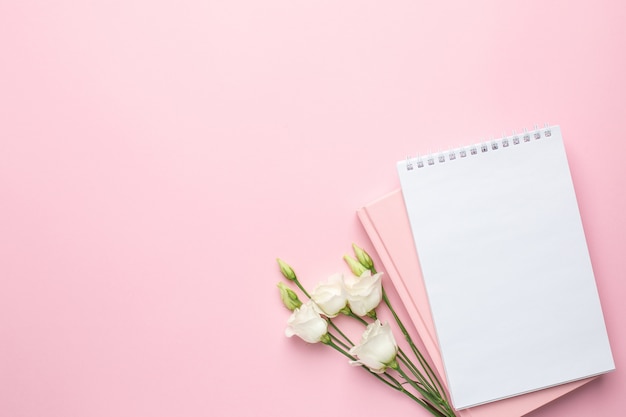 Beautiful white flower and notebook on pink