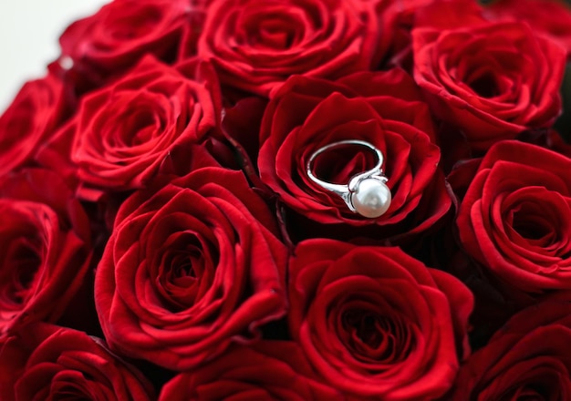 Beautiful white gold pearl ring and bouquet of red roses luxury jewelry love gift on Valentines Day and romantic holidays