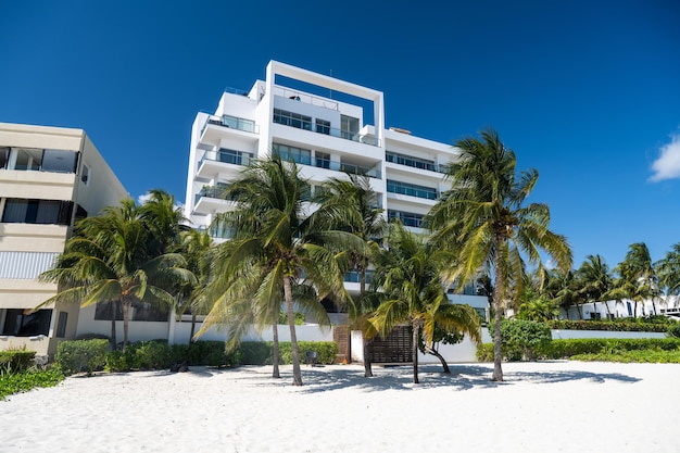 Beautiful white hotel building against blue sky and palms in front