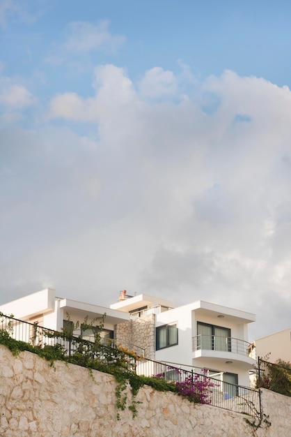 Beautiful white mansion behind a stone fence and a blue sky with clouds