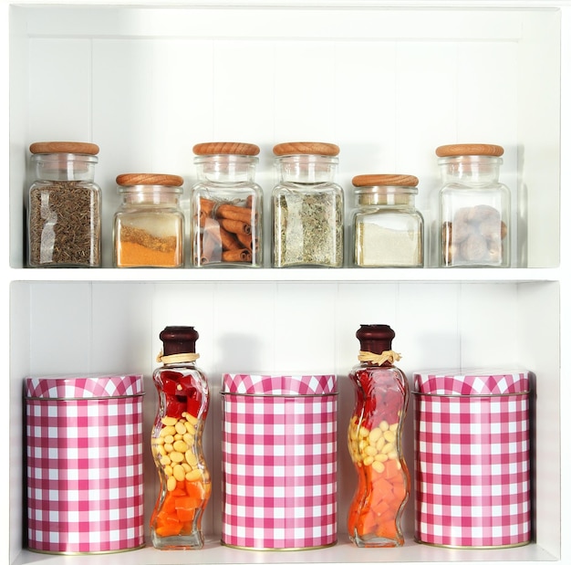 Beautiful white shelves with spices in glass bottles