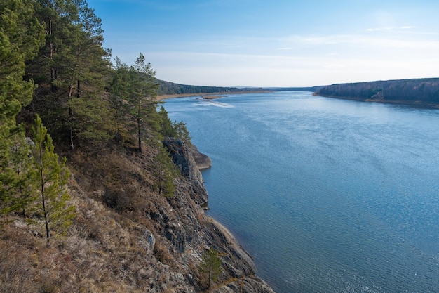 Beautiful wide autumn river among forests and rocky shore