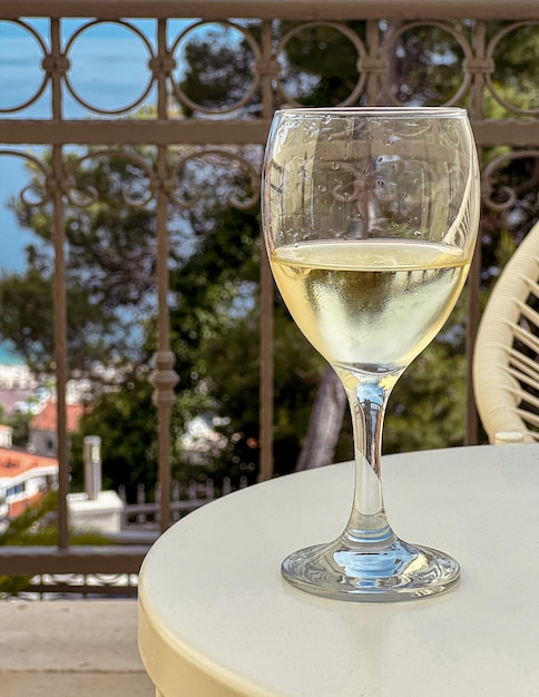 Beautiful wineglass with white wine standing on the table against the backdrop of sea Side view closeup Concept of leisure and travel