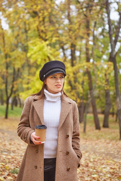 Beautiful woman in autumn park with coffee