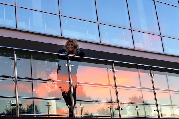 Beautiful woman on the background of the glass Windows at sunset