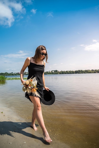 Beautiful woman barefoot walks by the lake warm water