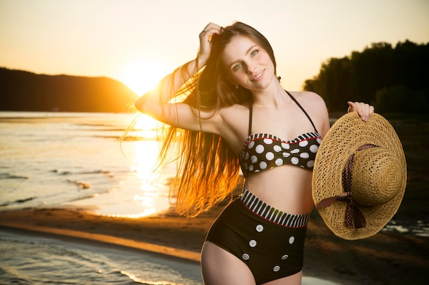 Beautiful woman in bikini on sunset background. Slim girl posing in a swimsuit