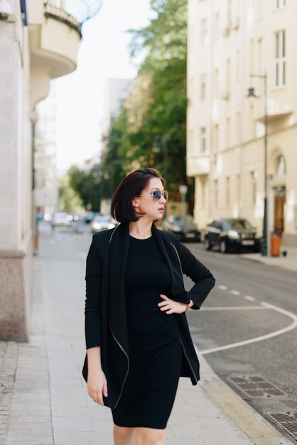 Beautiful woman in a black dress on a background of an urban landscape