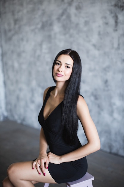 Beautiful woman in black dress. Over dark background.