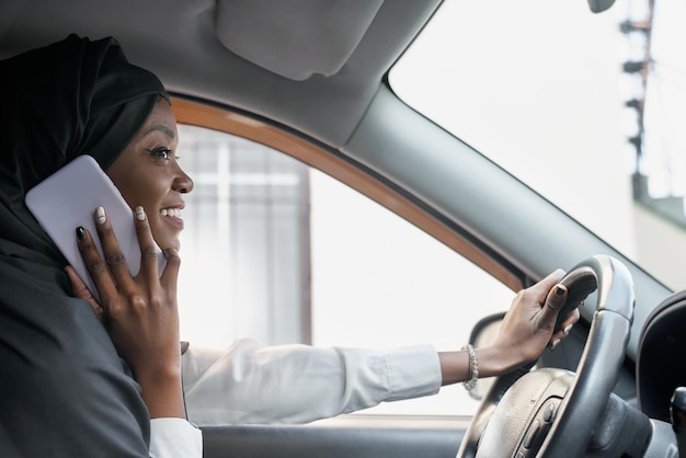 Beautiful woman in black hijab talking by phone in car