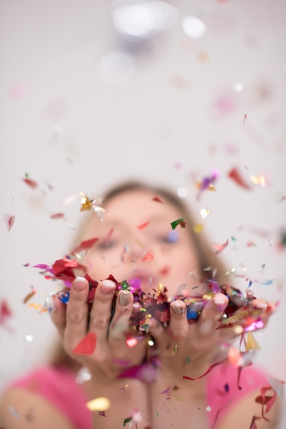 Beautiful  woman blowing confetti in the air party new years eve celebration isolated on white background