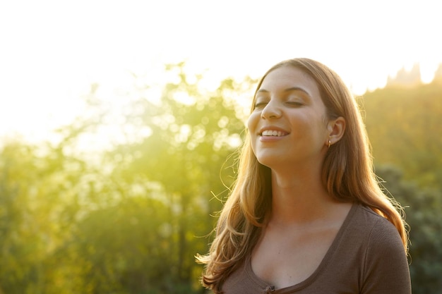 Beautiful woman breathing fresh air against natural background. Copy space.