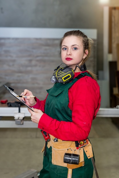 Beautiful woman carpenter making some notes on paper