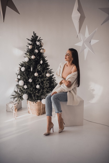 Beautiful woman celebrating New Year and Christmas at decorated Christmas tree and garlands