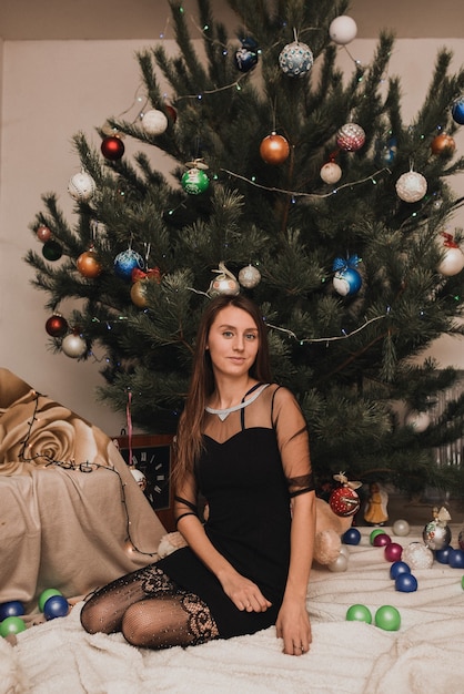 Beautiful woman celebrating New Year and Christmas at decorated Christmas tree and garlands