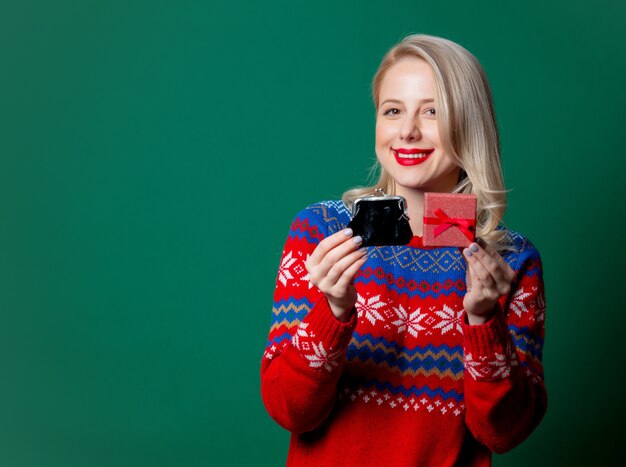 Beautiful woman in Christmas sweater with gift box and purse  