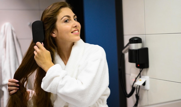 Beautiful woman combing her hair at the mirror