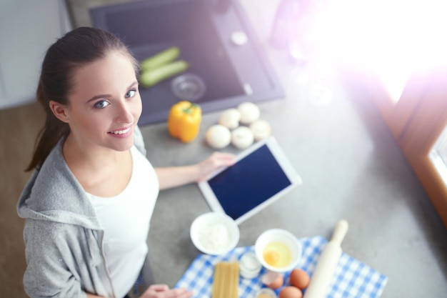 Beautiful woman cooking cake in kitchen standing near desk