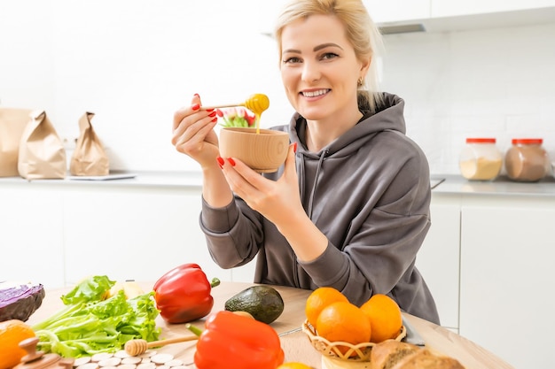 Beautiful woman cooking and having fun at the kitchen. Girl cooking healthy meal with honey in kitchen.