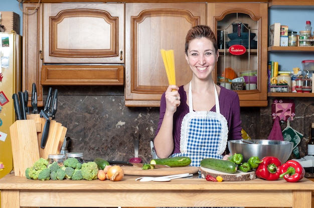 beautiful woman cooking vegetables with spaghetti