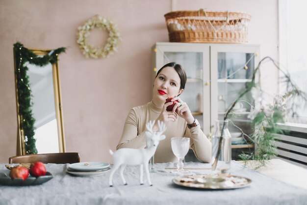 Beautiful woman in a cozy interior decorated for New Year and Christmas celebration Woman portrait on the background of a Christmas tree in a home interior and festive atmosphere