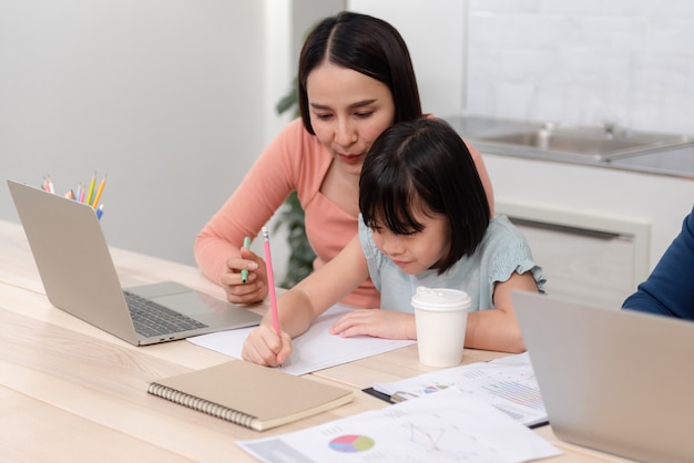 Beautiful woman And cute Asian girls drawing and writing on white paper The handsome man is working online.