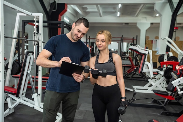 Beautiful woman doing intense sports in the gym with a young beautiful trainer