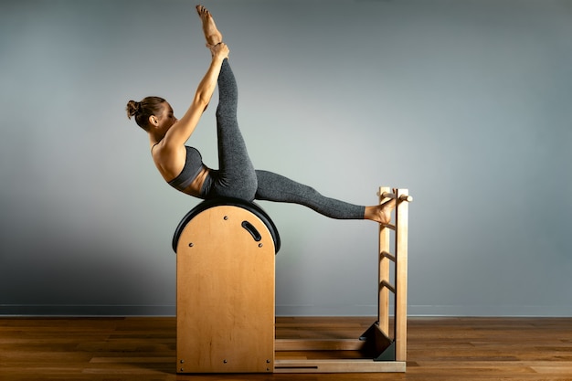 Beautiful woman doing pilates exercise training on barrels Barrel reformer correct posture healthy locomotor system