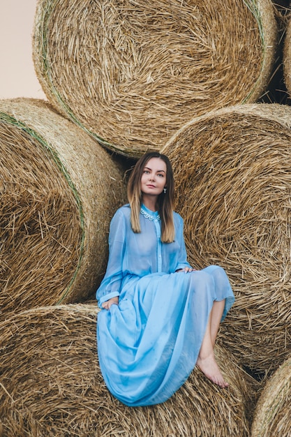 Beautiful woman in a dress on haystacks. 