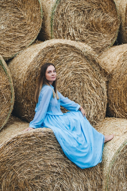 Beautiful woman in a dress on haystacks. 