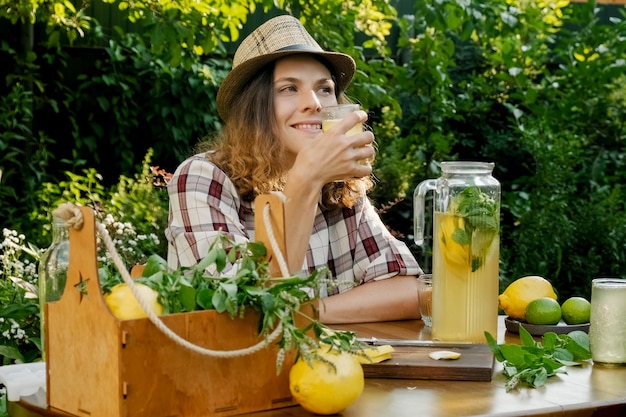 Beautiful woman drinking lemonade relaxing in summer backyard garden