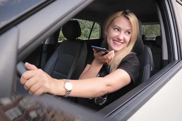 Beautiful woman driving a car is talking on mobile phone and smiling