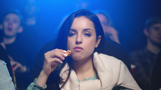 Beautiful woman eating in cinema Pretty girl watching film in movie theater