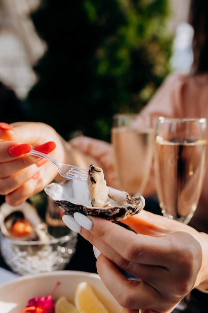 Beautiful Woman eating fresh oysters and drinking chilled prosecco wine on the summer sunset in restaurant Seafood delicacies