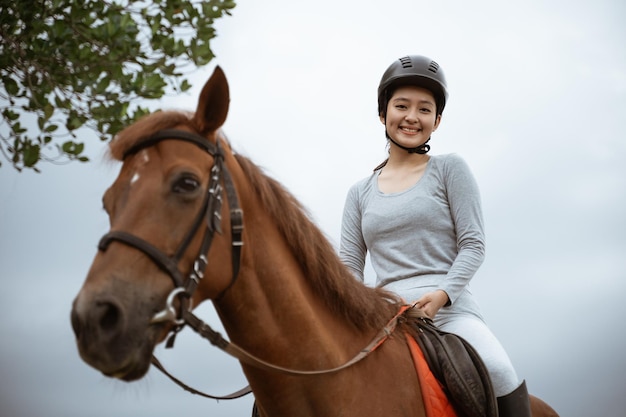 Beautiful woman equestrian athlete practicing horse riding on outdoor background