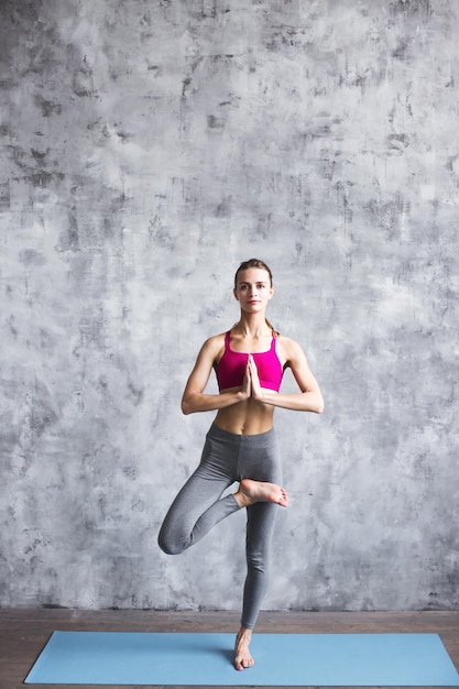 Beautiful woman exercising and doing the Yoga tree position