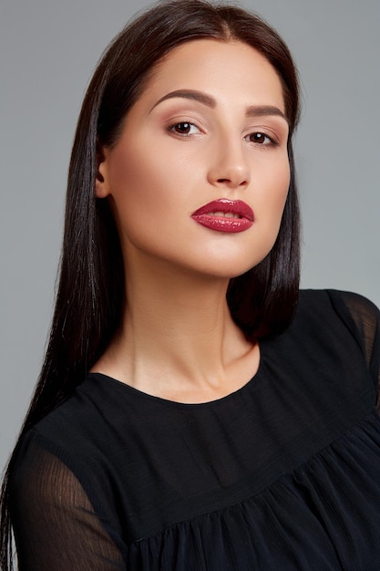 Beautiful woman face close up portrait young studio on gray. Woman in black dress